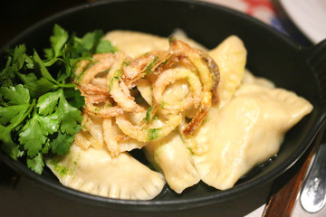 Delicious dumplings with cheese and onions in a bowl