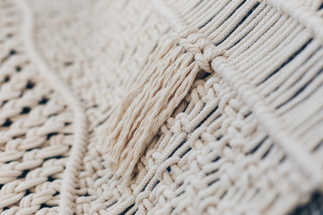 Detail of cream macrame decor displayed hanging on a wall.