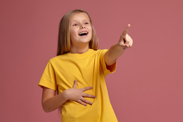 little girl in yellow t-shirt laughs pointing finger