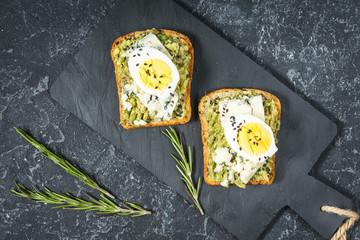 Egg and avocado sandwiches with cream cheese for healthy breakfast on stone background