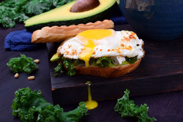 Sandwich with fried egg with liquid yolk and kale cabbage