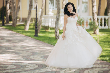 Fototapeta premium Beautiful bride in a white wedding dress on outdoors.