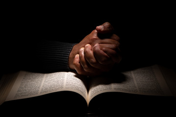 African American Man Praying with Hands on Top of the Bible