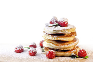 Pancakes. Homemade pancakes with raspberries and sugar powder on a wooden board.
