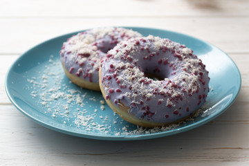 Donut on a blue plate on a wooden white background