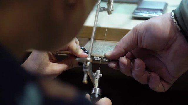 Jeweler makes a piece of jewelry - golden wedding ring