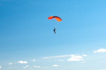 Parachutist soar on colorful parachutes across the boundless blue sky against the background of...