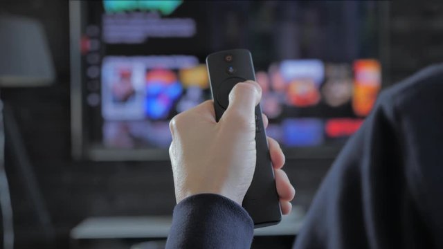 man holding a remote control and searching for streaming media to play