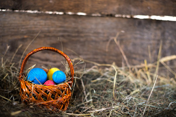 Easter eggs in a basket on a hay with a blurred background