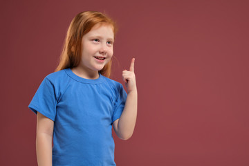 Portrait of cute redhead emotional little girl on red background