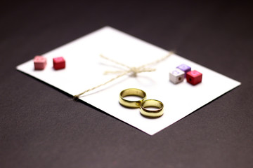 White envelope with banded with rope. Vintage wedding rings and little wooden cubes with hearts