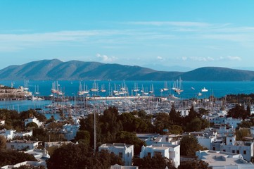 White buildings near the harbor in blue sea with mountains on the background