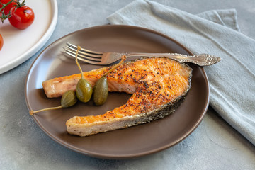 Fried salmon served on plate with caper apples.