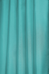 Vertical folds on green organza curtains