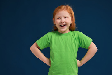 close up photo of little redhead emotional girl posing before camera on blue background