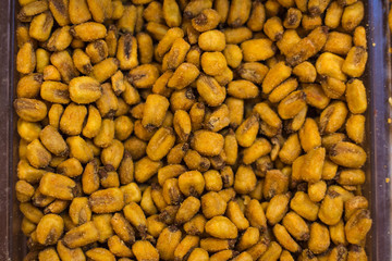 fried and salty corn yellow symmetry food concept on market mall counter background from above