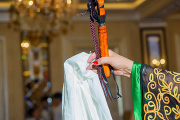 A woman holding a Kazakh national whip and a white handkerchief. Red manicure. Embroidery on...