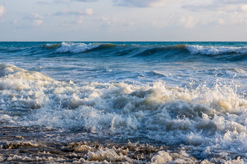 sea landscape is a pebbly beach with waves in white foam