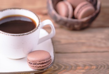 White cup of black coffee and homemade dessert chocolate macaroons on a wooden background