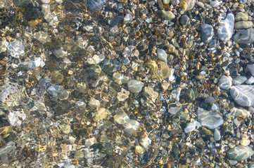 sea pebble beach with multicoloured stones, waves with foam