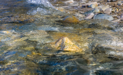 pebble stones on the sea beach, the rolling waves of the sea with foam
