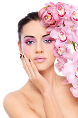 Fototapeta na wymiar Young beautiful woman with pink make-up and orchid flower over white background
