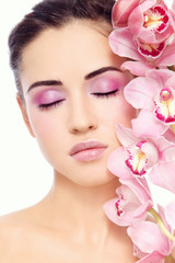 Fototapeta na wymiar Young beautiful woman with pink make-up and orchid