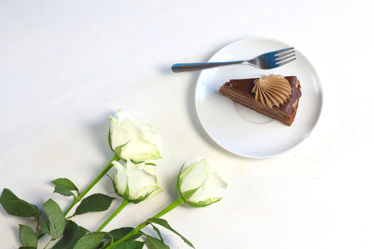 Three romance  white roses and piece of chocolate cake. Compliment congradulation for women. Celebration of happy birthday, anniversary, party