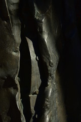 detailaufnahme einer bronzestatue eines priestern mit offenem mantel