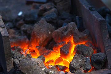 blacksmith furnace with burning coals, tools, and glowing hot metal workpieces