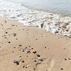 Small wet stones in the sand on the beach