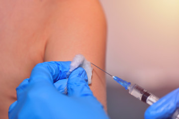 Close-up hands doctor or nurses are vaccination to patient using the syringe injected upper arm for treated. Doctor giving an injection to a patient