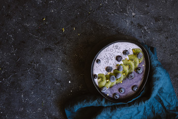 Vegan smoothie bowl with coconut yogurt, kiwi, blueberries and chia seeds on black background top...
