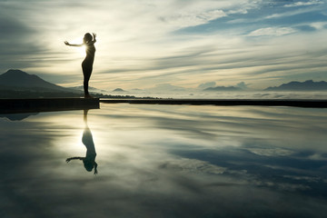 Unknown woman enjoys sunrise view at poolside