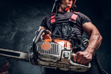 Low angle photo of a logger with a chainsaw in a dark studio  