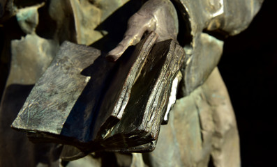 alte bronzestatue einer hand mit einem buch