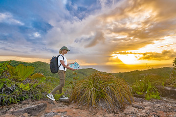 Woman tourist at top of mountain at sunset outdoors during a hike in summer..Girl traveler with a backpack  admires a tranquil natural landscape. Concept active recreation in mountains.