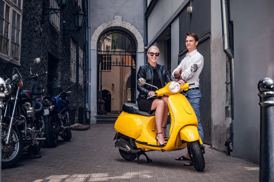 Romantic couple posing with retro Italian scooter in the old narrow street