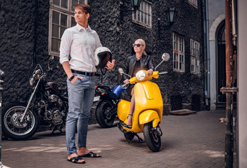 Naklejka na ściany i meble Romantic couple posing with retro Italian scooter in the old narrow street