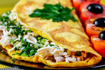 Omelet of chicken eggs stuffed with chicken meat with cheese and herbs. A tasty and healthy Breakfast is served with cherry tomatoes and black olives. The concept of proper nutrition and diet