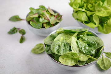 Fresh green salad leaves in a bowls on a gray concrete background, selective focus.