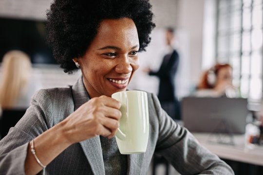 Happy African American woman enjoying in her coffee time at the office.