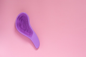 Purple hairbrush on pink background with copyspace. Equipment for combing and hairstyle making. - obrazy, fototapety, plakaty