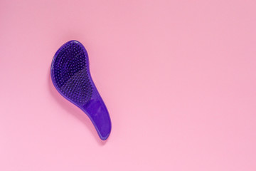 Pocket versipn of popular plastic hairbrush of dark purple color on pink background with copyspace. - obrazy, fototapety, plakaty