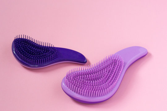 Close up female hairbrushes against hair falling for combing on pink background with copyspace. Professional salon equipment.