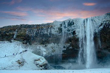 Morning sky with pink clouds behind Iceland Winter Waterfall