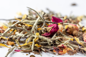 White tea with flowers, petals and rosebuds on white background. Close up of chinese white tea of premium luxury quality. Texture background macro photo. Bai Hao Yinzhen tea.