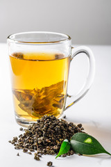 A Cup of green tea with dried large leaf tea and fresh tea leaves on a white background. Diet and healthy drink