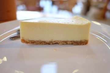 Close up a piece of cheese cake on a white plate with bokeh light background 