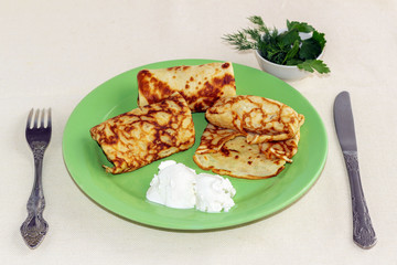 pancakes with filling and sour cream on a green plate